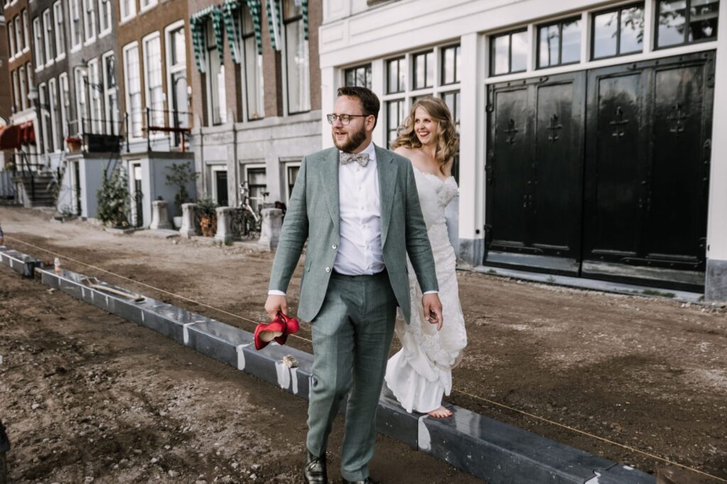 Man in pak met rode hakken in hand naast vrouw in witte jurk